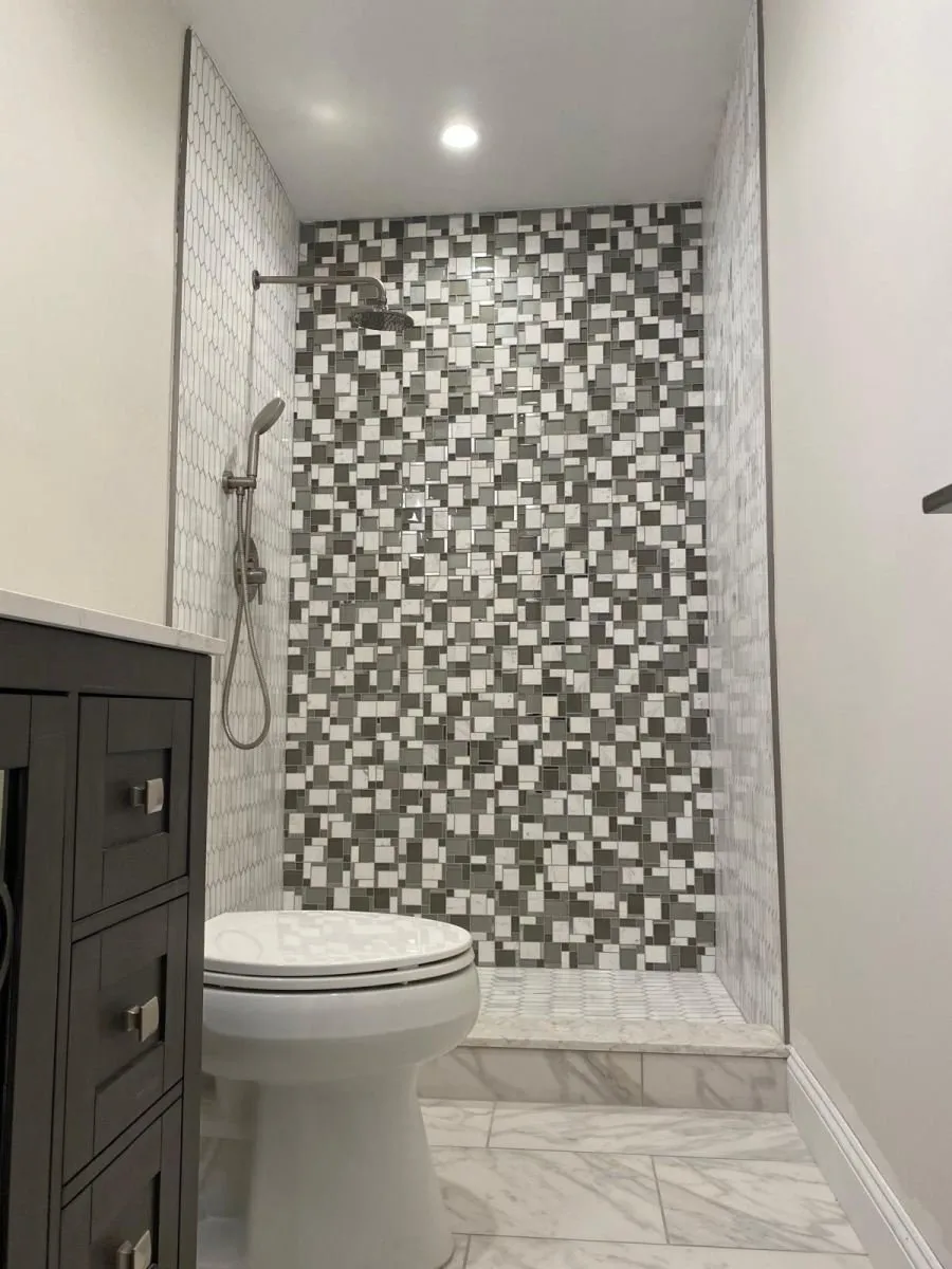 Mosaic tile shower with a dark wood vanity