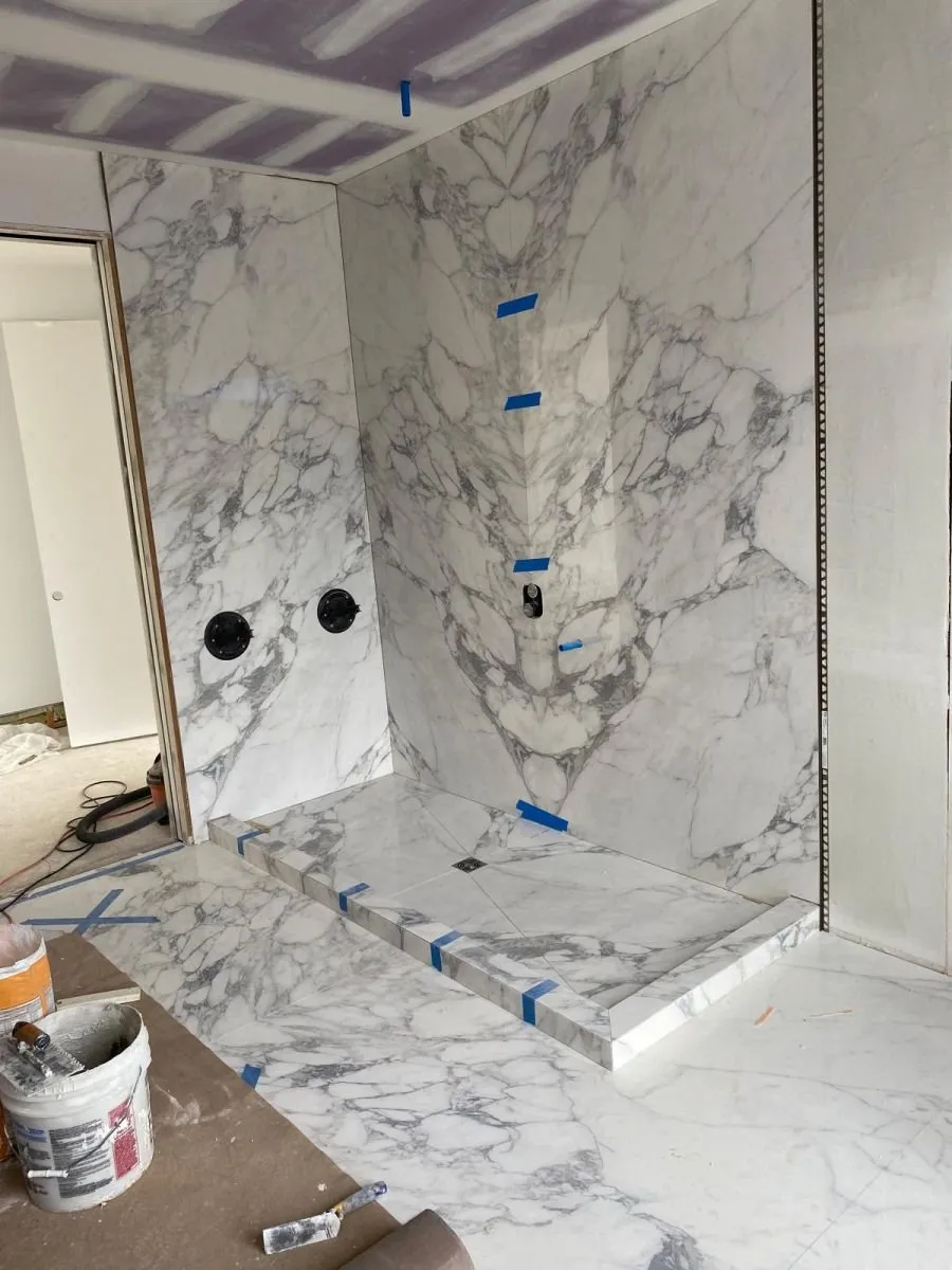 Book-matched marble slab shower walls being set during a bathroom renovation