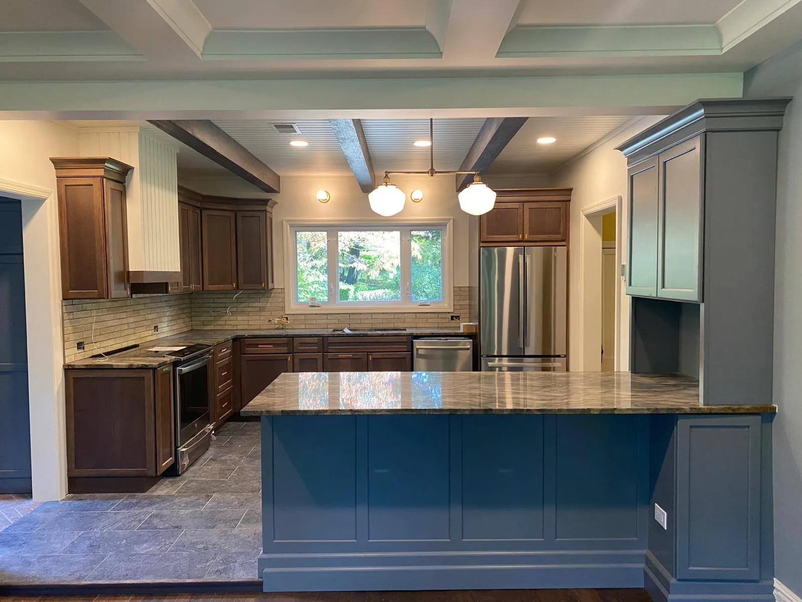 Renovated kitchen with a navy blue island and stone countertops in a Long Island home