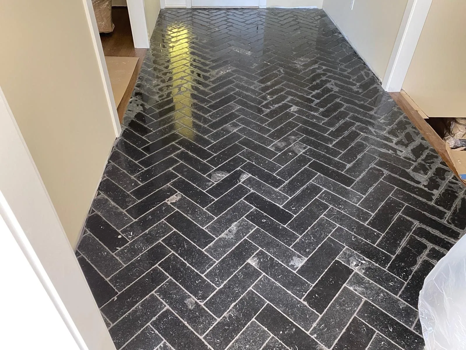 Black herringbone tile floor installed in a hallway