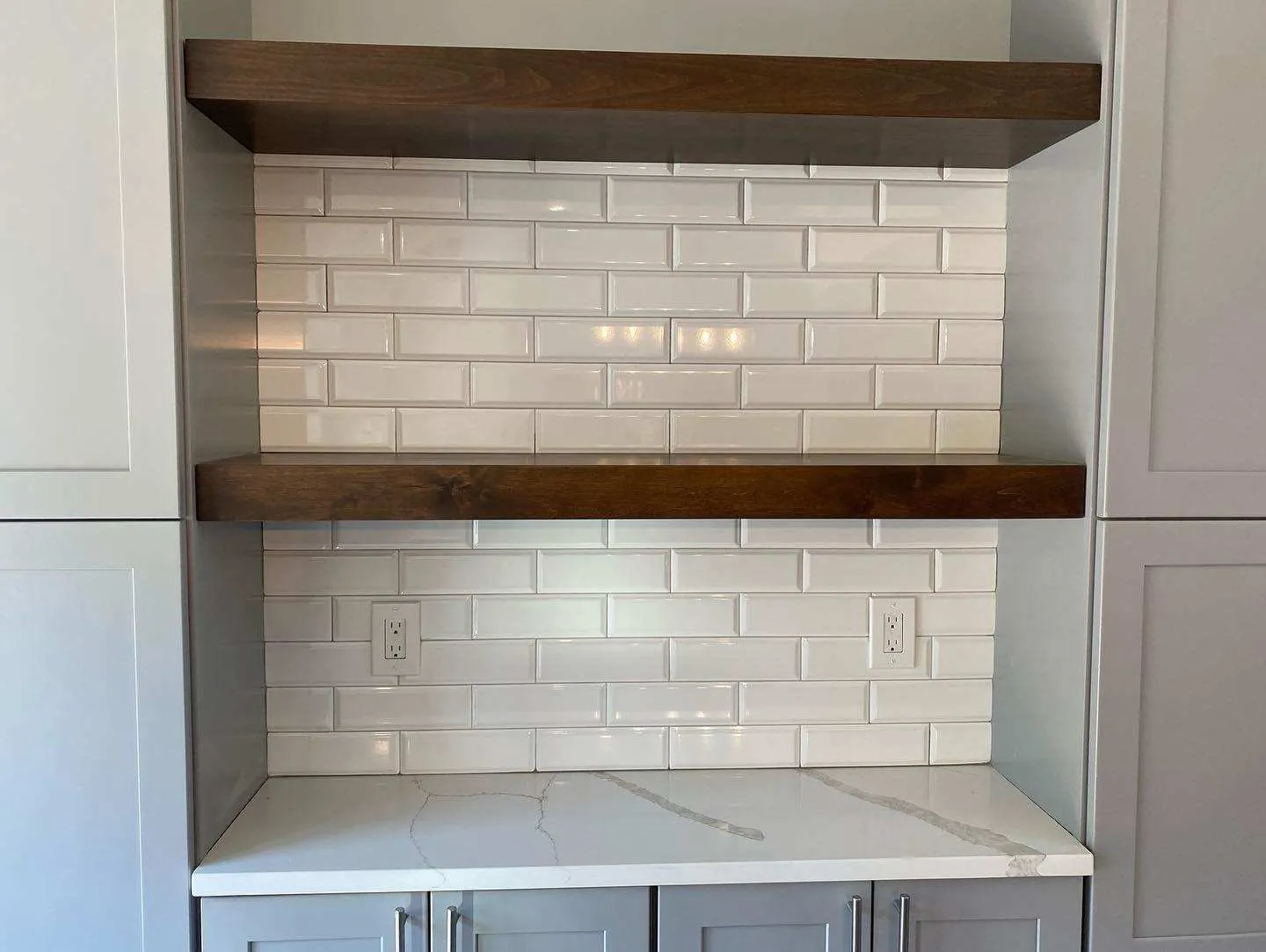 Kitchen with white subway backsplash, marble counter and floating wood shelves